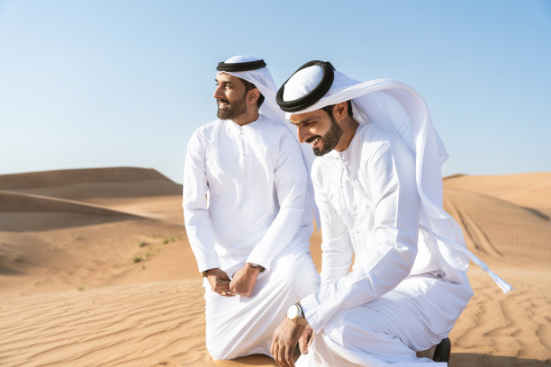 两个穿着阿拉伯坎杜拉的中东阿拉伯男子在沙漠中亲密接触图片下载
