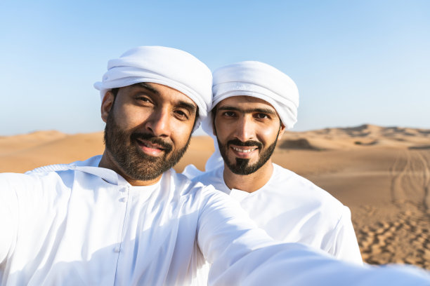 两个穿着阿拉伯坎杜拉的中东阿拉伯男子在沙漠中亲密接触图片下载