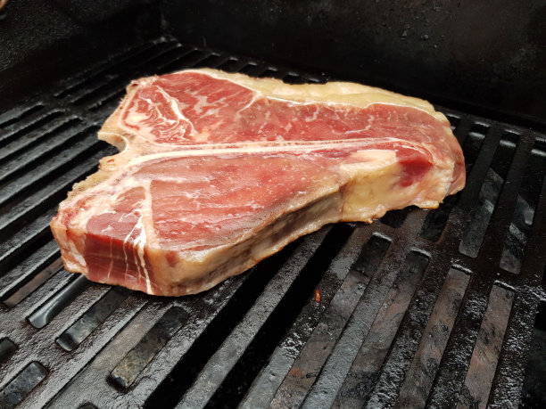 多汁的上等牛排在热烤架上滋滋作响的特写图片下载