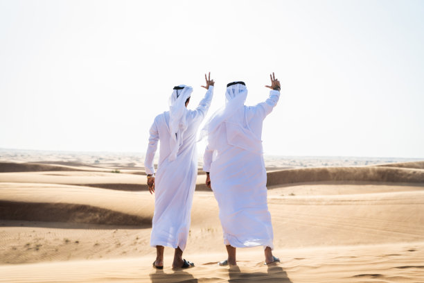 两个穿着阿拉伯坎杜拉的中东阿拉伯男子在沙漠中亲密接触图片下载