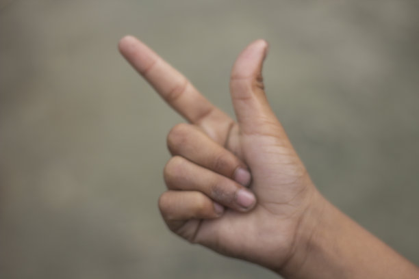 一只手的两个手指张开，其余的手指折叠，背景模糊图片下载