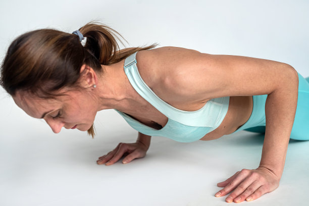 运动女性在健身房做俯卧撑，背景是白色的。图片下载