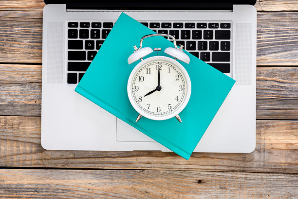 笔记本电脑，书和白色闹钟木制背景，俯视图。图片下载