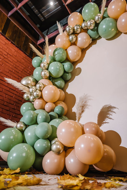 细节时髦的秋季装饰。拱门上装饰着绿色、棕色、金色的气球、干树叶，用于婚礼仪式。生日宴会的接待。庆祝洗礼。照片墙装饰文字空间。图片下载