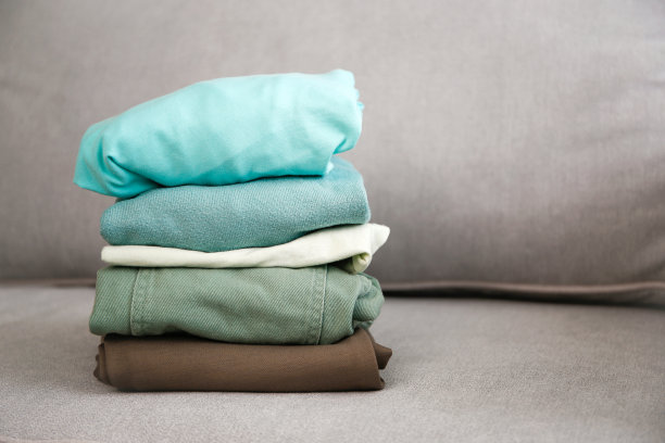 灰色的沙发上堆满了五颜六色的保暖衣服。图片下载