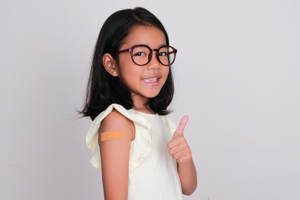 亚洲小孩的侧视图，微笑着竖起大拇指，手臂上涂着石膏图片下载