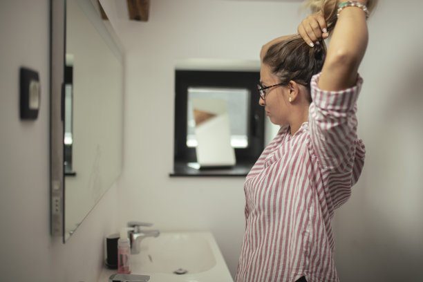 站在厕所里绑头发的女人的侧视图图片下载