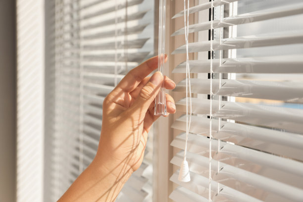 女子打开室内窗户上的水平百叶窗，特写图片下载