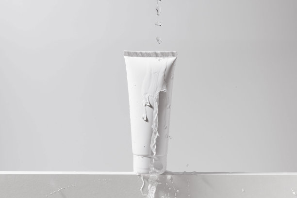 白色空白的保湿霜管，在一个孤立的背景上，有水滴从顶部流出。化妆品的概念是面部和身体的护理，美学和美容。图片为您的设计图片下载