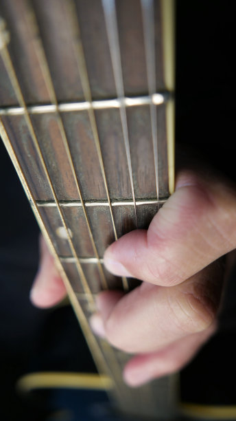 指板，特写镜头。弹原声吉他的人音乐家弹吉他，特写镜头。吉他脖子，吉他手臂。音乐工作室图片下载