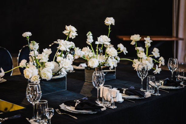 宴会装饰由鲜花、蜡烛、酒楼烛台组成。豪华婚宴。摆好桌子，摆好餐具。时尚的黑色丰富的装饰。生日，洗礼，大事。内部细节。图片下载