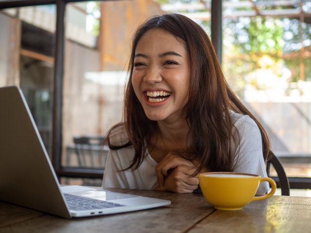 一个漂亮的亚洲女人坐在咖啡馆里开心地笑着。图片下载