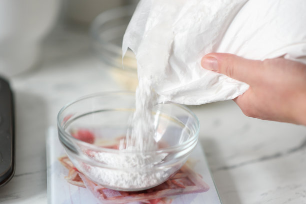 糖果师通过数字秤将糖粉倒入碗中。有选择性的重点。烹饪concept.Close-up。图片下载