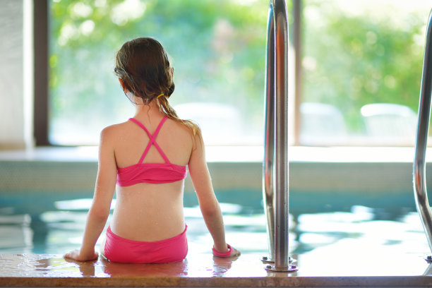 可爱的小女孩在室内游泳池玩充气环。学游泳的孩子。孩子们在玩水上玩具。图片下载