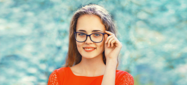 幸福的白人微笑的年轻女子戴着眼镜在春天花园鲜花背景的肖像图片下载