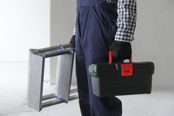拿着建筑工具的建筑杂工。房屋装修背景。图片下载