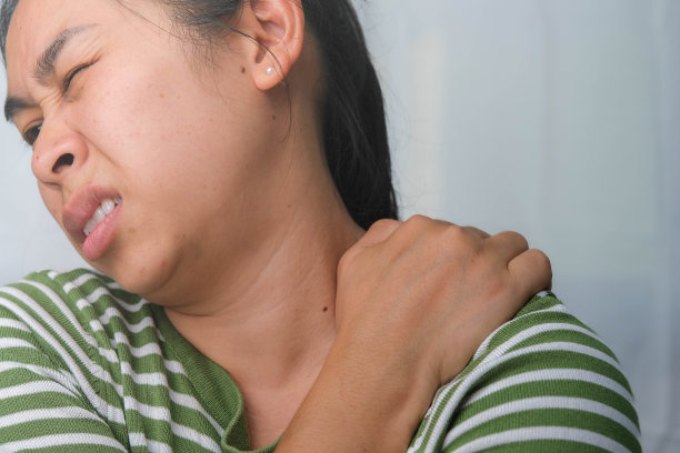 忧郁的年轻女子抱着她的脖子。劳累的女人按摩僵硬的脖子，绷紧的肌肉，劳累的工作。上臂疼痛。医疗保健和医药概念。图片下载