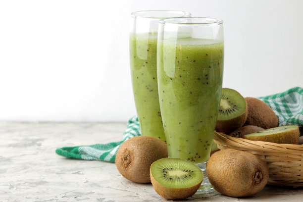 玻璃杯里的猕猴桃冰沙，旁边的大理石桌子上放着新鲜的猕猴桃片。水果饮料。图片下载