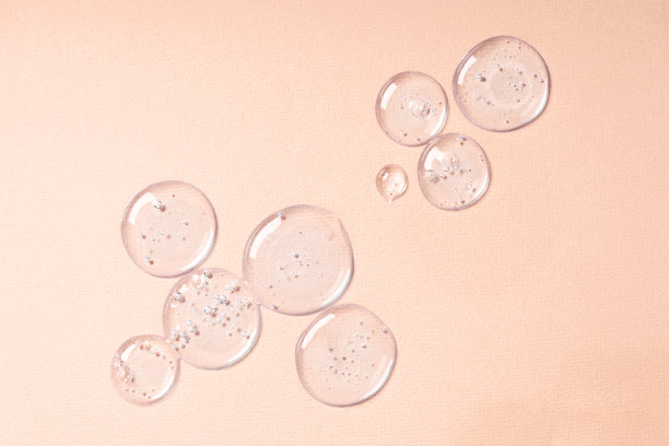 滴和涂抹的化妆品。米色背景上带有气泡的透明凝胶液滴图片下载