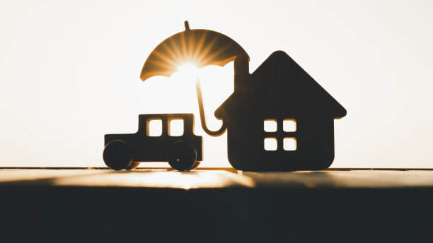 木桌上有雨伞的汽车和房子模型，有购买、保险或贷款房地产或物业的概念背景。图片下载