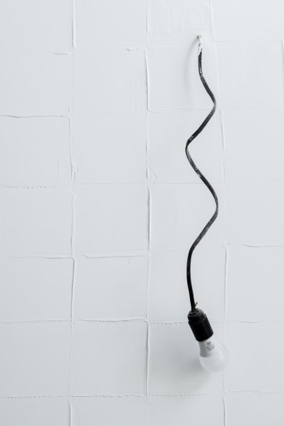 一根带灯泡的黑色电线从白色砖墙里伸出来图片下载