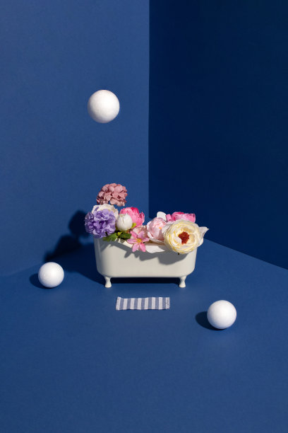 浴缸里装满了花，蓝色墙壁的角落里有白色的泡泡。最小的创意概念。图片下载