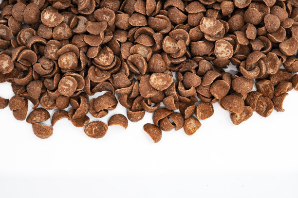 巧克力玉米片早餐库存照片。白色的背景是巧克力麦片。一大群巧克力味玉米片的俯视图。可可。可可。早餐。美味。脆脆的。麦片图片下载