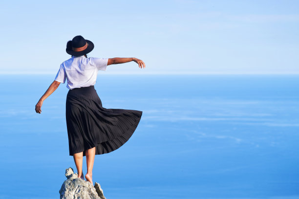 女人站在岩石上自由地望着大海图片下载