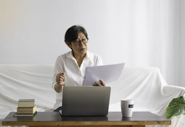 聪明的老太太看纸，用笔记本电脑工作图片下载