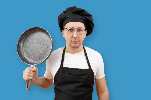 厨师手里拿着煎锅，背景是蓝色的。烹饪和人的概念。图片下载