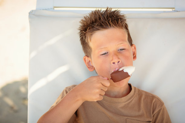 帅哥坐在沙滩上吃冰淇淋图片下载