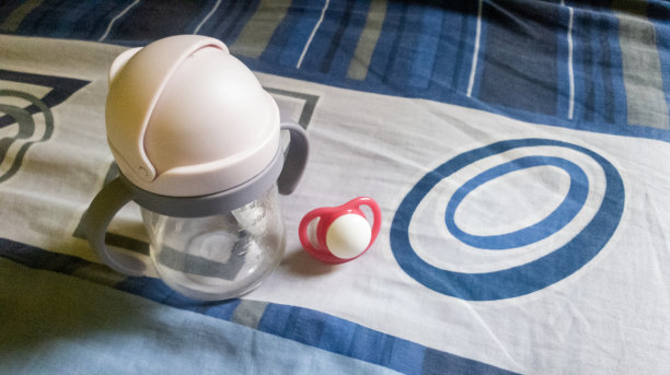 卧室的床上放着装有牛奶和奶嘴的奶瓶图片下载