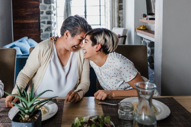 拉丁美洲，拉丁裔家庭，墨西哥的拉丁老年母亲和成年女儿在家里拥抱和欢笑图片下载