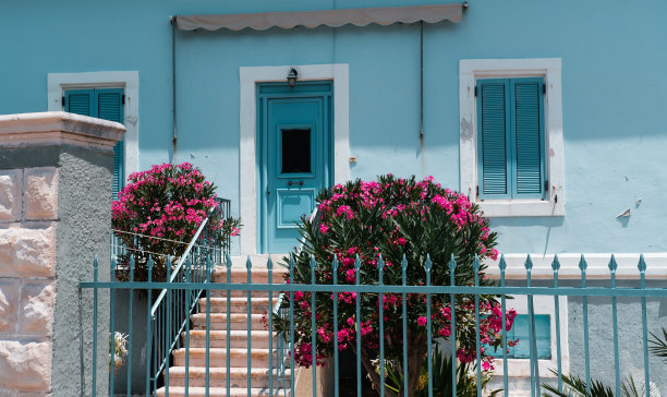房子漆成蓝色，有木制百叶窗和门，花园有露台和夹竹桃，有栅栏图片下载