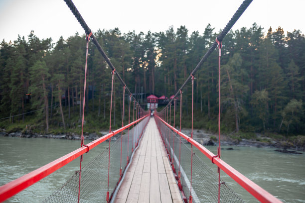一座悬索桥，横跨在山间宽阔的河流上。图片下载