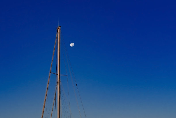 满月和帆船桅杆在暮色中深蓝色的天空图片下载