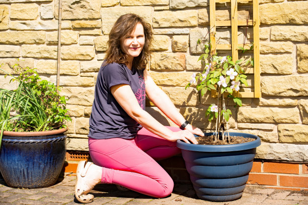 微笑的女士拿着一朵攀缘的铁线莲。图片下载