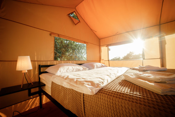 舒适的开放式豪华野营帐篷的内部，在日落时分，里面有灯光。豪华户外露营帐篷，适合夏季度假度假。生活方式的概念图片下载