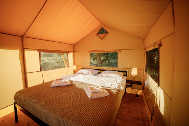 舒适的开放式豪华野营帐篷的内部，在日落时分，里面有灯光。豪华户外露营帐篷，适合夏季度假度假。生活方式的概念图片下载