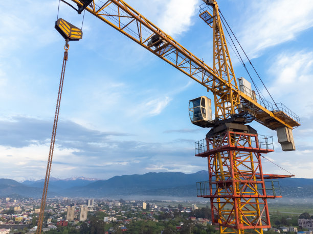 在美丽的山峦和天空的背景下，从一架无人驾驶飞机上的建筑起重机机舱的特写镜头。建筑的概念图片下载