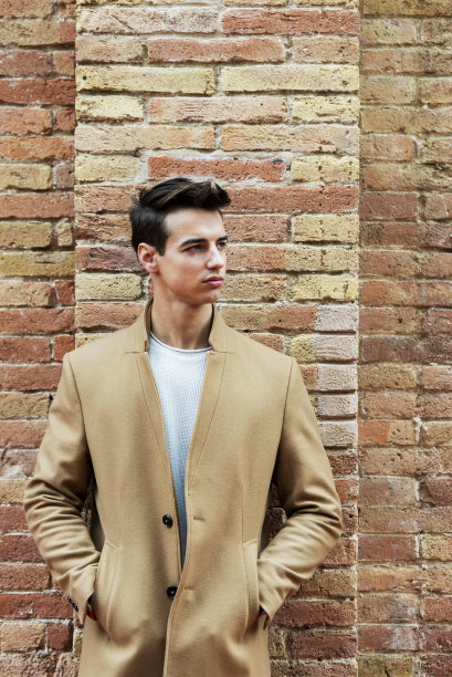 年轻人穿着冬衣走在街上。一个留着现代发型，棕色外套的年轻人。图片下载