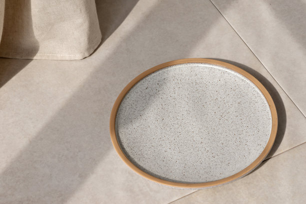 空灰色陶瓷盘在米色石材餐桌背景上配以阳光光影，美学极简的餐厅或咖啡厅商业品牌模板，复制空间图片下载