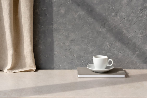 极简美学可持续的家居静物用咖啡杯放在中性米色的桌子上，用亚麻窗帘和阴影放在灰色的空混凝土墙的背景下，优雅的房间室内设计的背景图片下载