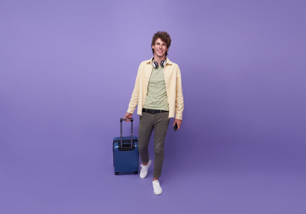 快乐的年轻游客拿着智能手机和行李去度假，孤独的紫色背景。图片下载