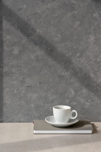 极简主义的美学构图用米色桌面的咖啡杯和空灰色混凝土墙上的阳光阴影，家居室内设计中性背景，复制空间，早晨咖啡的概念图片下载
