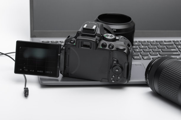 在笔记本电脑和镜头旁边放着一台数码相机图片下载