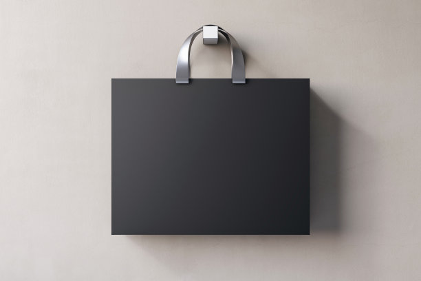 购物或目前的概念，在空白的黑色纸袋与银色手柄和地方的公司标志或广告文字在浅米色的墙壁背景前视图。3D渲染，模拟图片下载