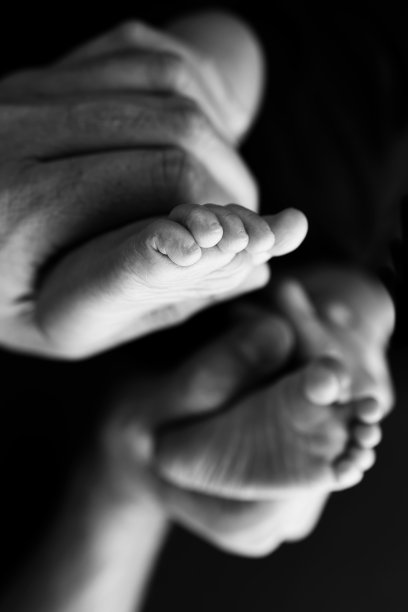 黑色和白色阴影美丽形状的母亲的手，抱着小新生儿的脚在黑色背景的爱，关怀，家庭的安全与保护，孩子与早产概念或新生儿重症监护图片下载