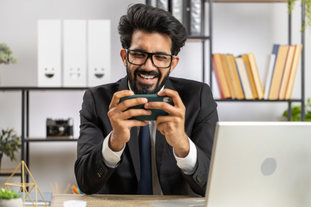 印度商人在智能手机上玩令人兴奋的手机应用程序庆祝赢得射击游戏图片下载