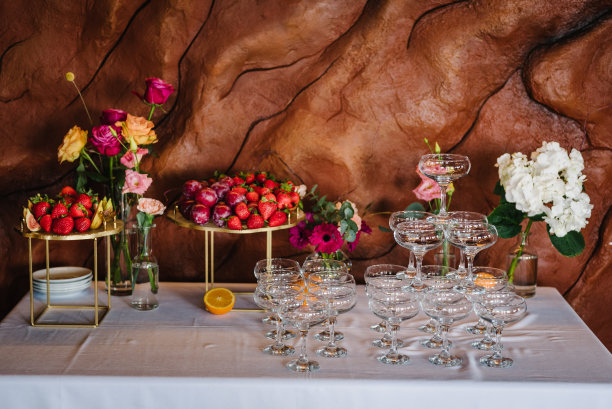 一盘水果，草莓，李子，无花果，鸡尾酒的杯子。糖果酒吧。美味的婚宴豪华的仪式。餐桌装饰粉红色的花朵玫瑰，用于宴会上的生日聚会。图片下载